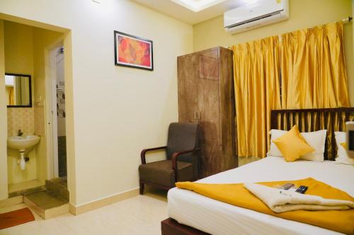 a bedroom with a bed and a chair and a sink at JACK'S DEN residency in Puducherry