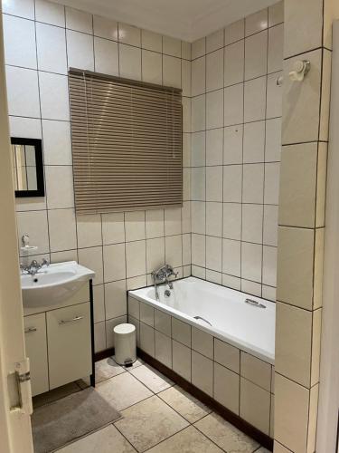 ein Badezimmer mit einer Badewanne und einem Waschbecken in der Unterkunft Thorntree Self Catering Apartment, Witbank in Witbank