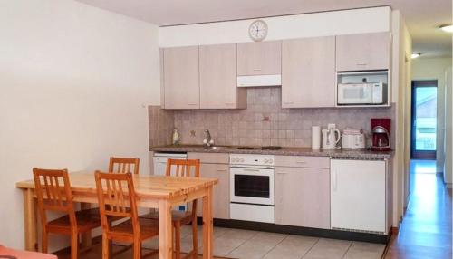 een keuken met witte kasten en een houten tafel en stoelen bij Appartement Spacieux aux Portes du Soleil in Torgon