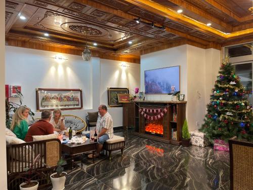 un groupe de personnes assises à une table avec un arbre de Noël dans l'établissement OLAGI HOTEL, à Khu Chi Lăng