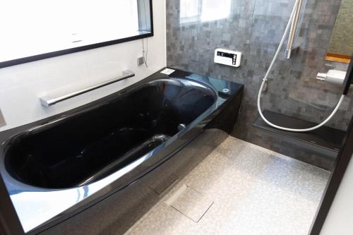 a bathroom with a black tub and a shower at 森の風 in Higashiizu