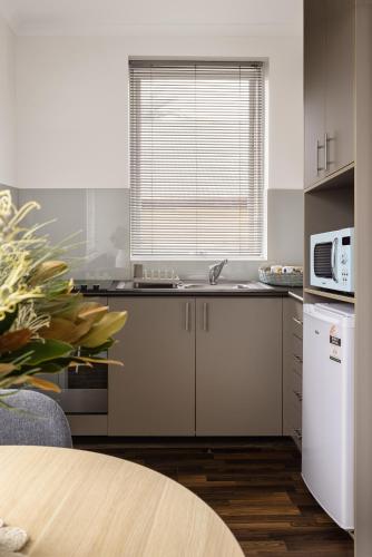 a kitchen with a sink and a white refrigerator at MAC St Kilda Blessington St by Melbourne Apartment Collection in Melbourne