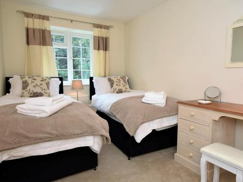 a bedroom with two beds and a dresser and a window at 3 Bed in Smarden 58544 in Smarden