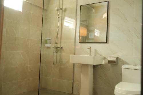 a bathroom with a shower with a sink and a toilet at UniHome Suite in Bintulu