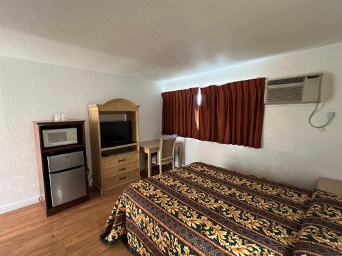 a hotel room with a bed and a desk and a television at Sherwood Motel in Palmdale