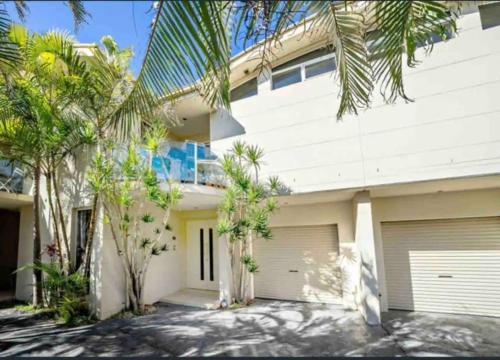 a white house with palm trees in front of it at Whitewater Beach House in Old Bar
