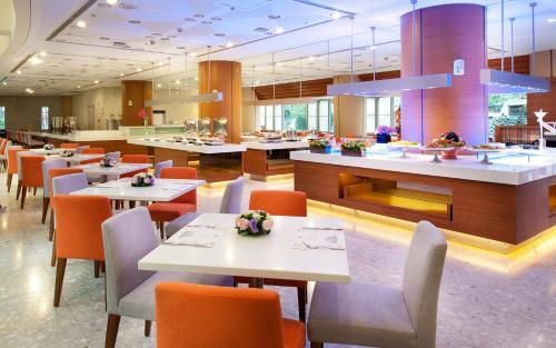 a restaurant with white tables and orange chairs at Howard Civil Service International House in Taipei