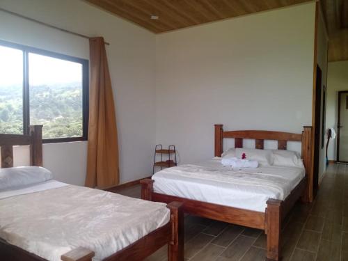 two beds in a room with a window at Vulkan Arenal Amazing View Lodge 4 WD in El Castillo de la Fortuna