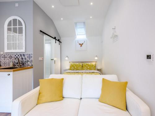 um sofá branco com almofadas amarelas num quarto em 1 Bed in Dereham 78596 em Bawdeswell