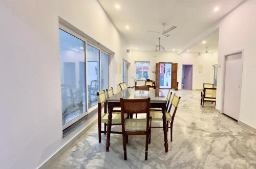 a dining room with a table and chairs and windows at 26 LaPorte in Pondicherry
