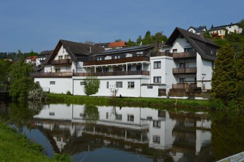 a large white building next to a river at Ferienwohnungen Pfeil in Nieder-Werbe