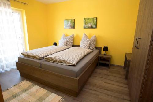 a bedroom with a bed with yellow walls at Ferienwohnungen Ankerplatz in Scheid
