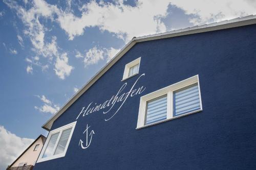 ein blaues Gebäude mit Schreiben auf der Seite in der Unterkunft Ferienwohnungen Heimathafen in Edersee