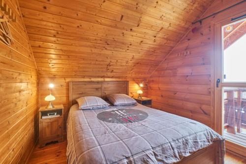 ein Schlafzimmer mit einem Bett in einer Holzhütte in der Unterkunft Le chalet Céline in Le Dévoluy