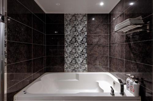 a bath tub in a bathroom with black tiles at BELMORE Hotel in Busan