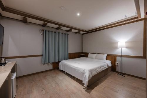 a bedroom with a bed and a table and a lamp at BELMORE Hotel in Busan