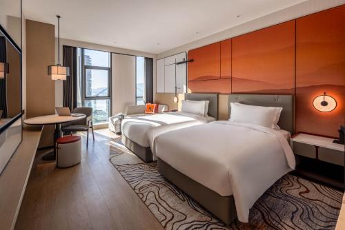 um quarto de hotel com duas camas e uma mesa em Grand Mercure Yichang Waitan em Yichang