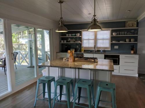 una cocina con una isla con 4 taburetes en Pineapple Cottage, en Saint Simons Island