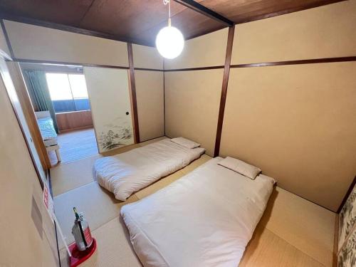 een kleine kamer met 2 bedden en een licht bij ～Fushimi Inari～露天風呂付の一棟貸切のゲストハウス in Kyoto