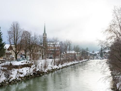 a river with snow covered trees and a church at Apartment in Niedernsill near Ski Slopes in Niedernsill