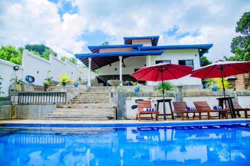 a house with chairs and umbrellas next to a swimming pool at Peaceful Villa with pool near Hikkaduwa in Ambalangoda
