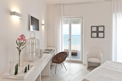 a white bedroom with a desk and a bed and a window at Hotel Torremaura in Milano Marittima