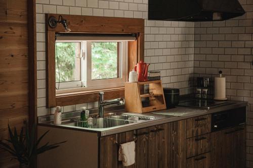 eine Küche mit einem Waschbecken und einem Fenster in der Unterkunft 美瑛森林木屋 - 小紅帽 in Biei