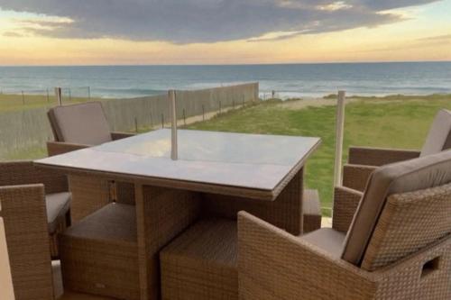 a table and chairs with the ocean in the background at Whitewater Beach House in Old Bar