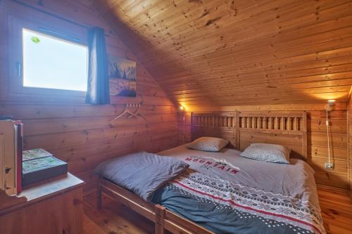 a bed in a log cabin with a window at Le chalet Virginie in Le Dévoluy