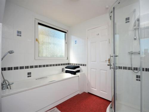 ein weißes Bad mit einer Badewanne und einem Fenster in der Unterkunft 5 Bed in Tenby 56683 in Penally