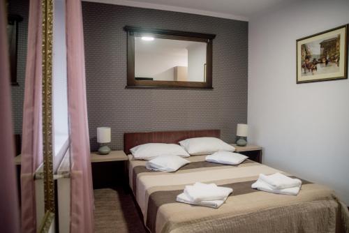 a bedroom with two beds and a mirror on the wall at Carnival City Hotel Oradea in Oradea