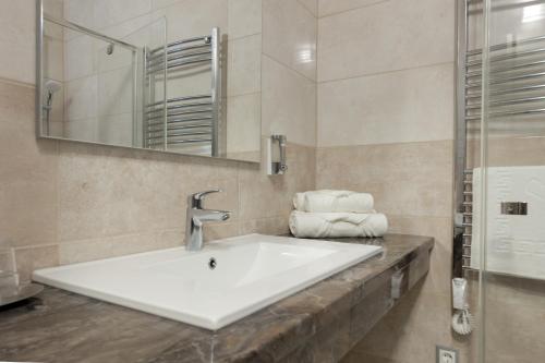 ein Badezimmer mit einem Waschbecken, einem Spiegel und Handtüchern in der Unterkunft Bubble Hotel és Rendezvényközpont in Zalaegerszeg