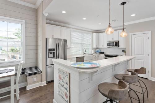 una cucina con mobili bianchi e un bancone con sgabelli di 400 Ocean Blvd. #1200 a Golf Retreat
