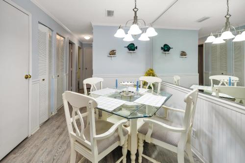 a dining room with a glass table and white chairs at Ocean Walk H-14 in Saint Simons Island