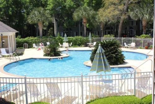 a large swimming pool with chairs and an umbrella at Ocean Walk H-14 in Saint Simons Island