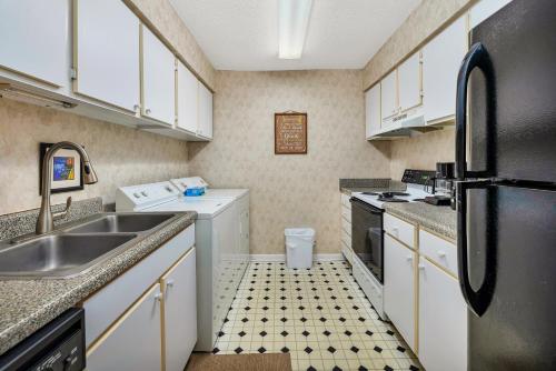 La cuisine est équipée de placards blancs et d'un réfrigérateur noir. dans l'établissement Ocean Walk E-6, à Île de Saint-Simon