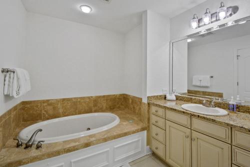 ein Badezimmer mit einer Badewanne, einem Waschbecken und einem Spiegel in der Unterkunft Salt Therapy in Saint Simons Island