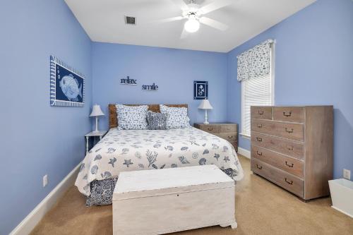 Schlafzimmer mit blauen Wänden, einem Bett und einer Kommode in der Unterkunft Carolyns by the Sea in Saint Simons Island