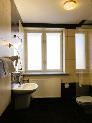 un bagno con lavandino e servizi igienici e due finestre di Hotel Łazienkowski a Varsavia
