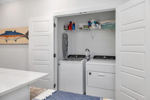 een keuken met witte kasten en een wasmachine en droger bij Baisden Cottage in Saint Simons Island