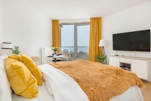 a bedroom with a bed with yellow pillows and a flat screen tv at Sunny Coast Studio in Pobierowo by Renters in Pobierowo