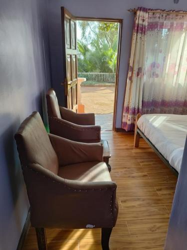 a living room with a chair and a bed and a door at Zack's Serene House in Kisii