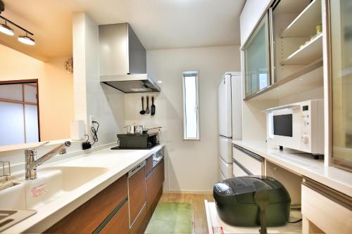 eine Küche mit einer Spüle und einer Mikrowelle in der Unterkunft kameido k hotel in Tokio