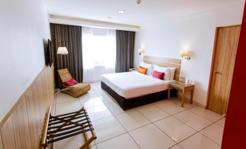 um quarto de hotel com uma cama e uma cadeira em Wonderla Resort em Kumbalgod