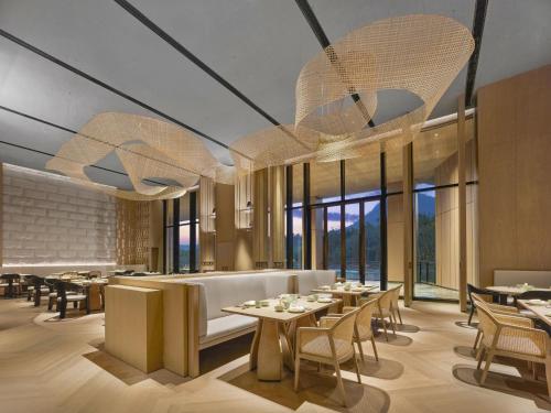 a restaurant with tables and chairs and large windows at Hilton Nanjing Niushoushan in Nanjing
