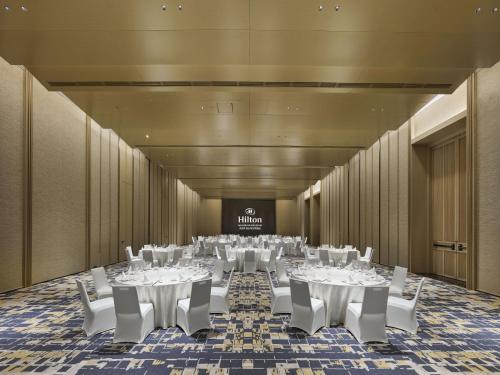 a large room with white tables and white chairs at Hilton Nanjing Niushoushan in Nanjing