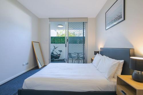 a bedroom with a white bed and a balcony at 'Attiva' A Brisbane Gem with Pool and Private Patio in Brisbane