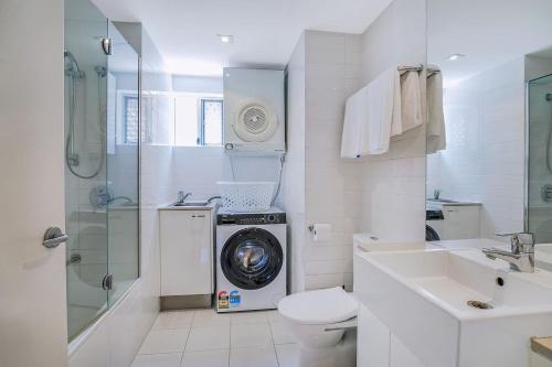 une salle de bains blanche pourvue d'un lave-linge. dans l'établissement 'Attiva' A Brisbane Gem with Pool and Private Patio, à Brisbane
