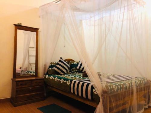 a bedroom with a bed with a canopy and a mirror at Sigiri Sunanda Home Stay in Sigiriya