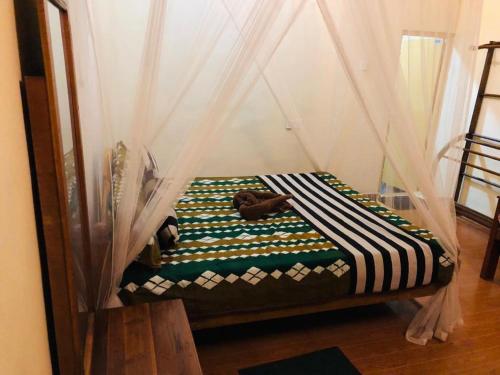 Sigiri Sunanda Home Stay في سيجيريا: سرير صغير في غرفة ذات ستارة